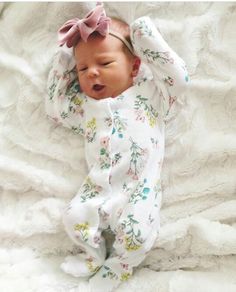 a baby laying on its back with a bow in it's hair and wearing pajamas