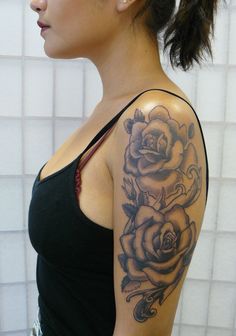 a woman with a tattoo on her arm and shoulder is standing in front of a tiled wall