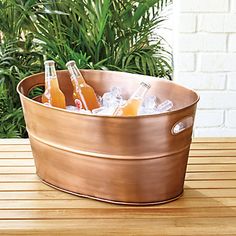 a metal tub filled with drinks on top of a wooden table