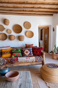 a living room filled with lots of pillows and baskets on the wall above it's couch