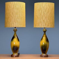 two yellow lamps sitting on top of a wooden table