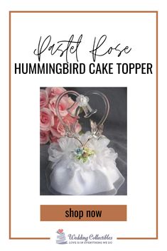 the hummingbird cake topper is shown with pink roses and white flowers on it