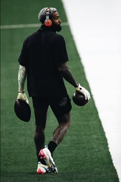 a man in black shirt and white gloves holding a football on green field with grass