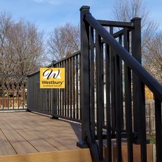 a wooden deck with black iron railings and a sign for westbury on it