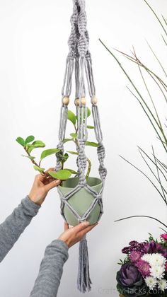 someone is holding up a plant in a macrame style pot holder with two hands