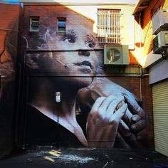 a mural on the side of a building with a woman holding her hand up to her face