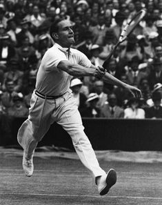 a man swinging a tennis racquet on top of a tennis court in front of an audience