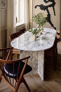 a dining room table with chairs and a vase filled with flowers on top of it