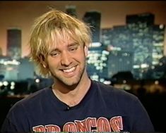 a man with blonde hair smiling at the camera