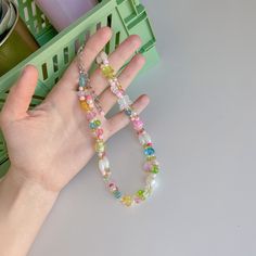 a person's hand holding two bracelets with multicolored beads on them