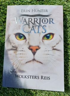 a book about warriors cats is laying on the grass