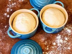 three blue dishes with dough in them sitting on a brown counter top next to a bowl