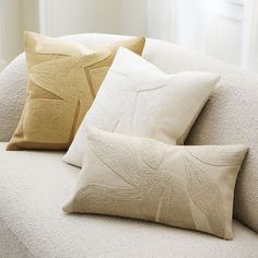 three pillows sitting on top of a white couch