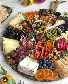 a platter filled with cheese, crackers, fruit and nuts next to oranges