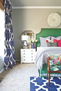 a bedroom with green headboard and white bedding, blue rug on the floor