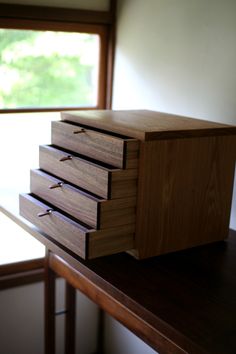 a wooden box sitting on top of a table next to a window with trees in the background