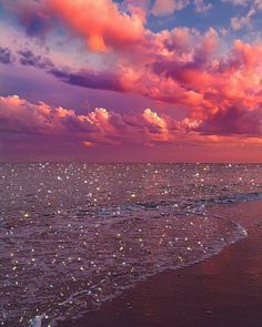 the sky is pink and purple over the water at the beach with stars in it