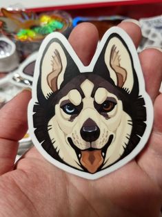 a hand holding a sticker with a dog's face painted on the side