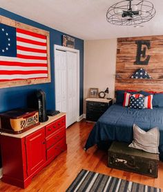 a bedroom decorated in red, white and blue with an american flag on the wall