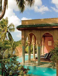 an outdoor swimming pool surrounded by palm trees and greenery with lounge chairs on the side