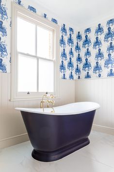 a bathroom with blue and white wallpaper and a claw foot tub in the corner