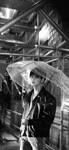 black and white photograph of a woman holding an umbrella in the rain, wearing leopard print pants