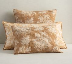 two pillows sitting on top of each other in front of a white and beige wall