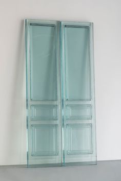 two glass doors sitting next to each other on a white wall in an empty room