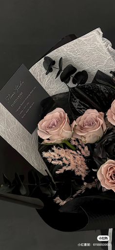 a bouquet of pink roses sitting on top of a black box