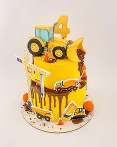 a birthday cake decorated with construction vehicles and cars on it's sides, including the number four