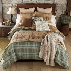 a bed with pillows and blankets on top of it next to a stone wall in a bedroom