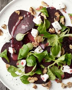 beet salad with goat cheese and walnuts on a white plate sitting on a wooden table