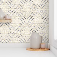 two white vases are sitting on a shelf in front of a patterned wallpaper