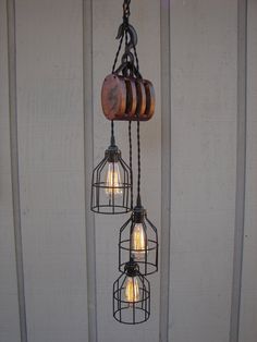 three light fixtures hanging from the side of a building with wood and metal caged lights