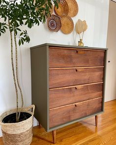 a wooden dresser sitting on top of a hard wood floor next to a potted plant