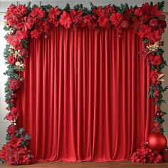 a red curtain with flowers and greenery on the top is in front of a christmas ornament