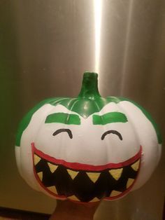 a green and white pumpkin with teeth painted on it