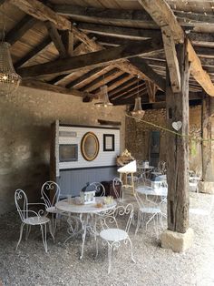 an outdoor dining area with tables and chairs under a wooden structure that is made out of wood planks