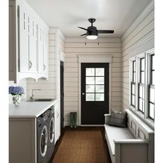 a washer and dryer in a room with white walls, wood floors and black door