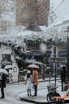 people are walking in the snow with umbrellas