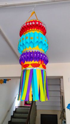 a multicolored paper lantern hanging from the ceiling in a house with stairs leading up to it