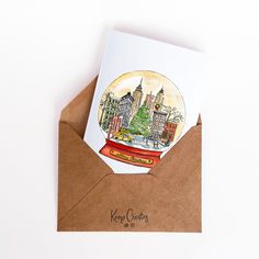 an envelope with a christmas card inside and a snow globe in the middle on top