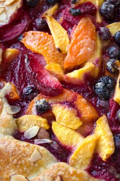 fresh fruit pie with almonds, blueberries and peaches on top is ready to be eaten