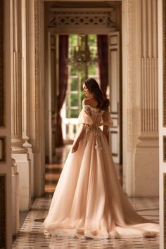 a woman in a long dress is walking down the hall