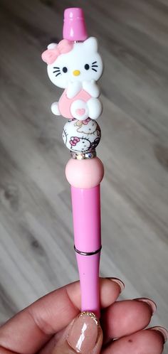 a person holding a pink hello kitty pen in their left hand, with the top part of it sticking out