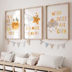 three framed children's prints on the wall above a bench with storage bins