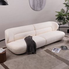 a white couch sitting on top of a rug in a living room next to a potted plant