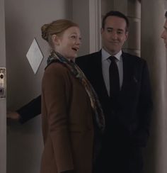 two men and a woman are standing in front of a door talking to each other