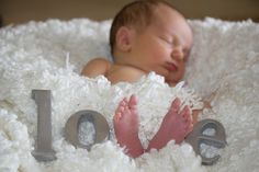 a baby is laying down in a blanket with the word love spelled out next to it