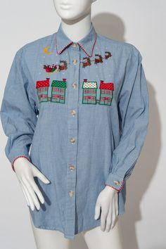 "This is a lovely Christmas themed denim blue button down by Jennifer Blair, Northern Isles Petites. The shirt if made from a soft denim blue, with red & white trim around the collar and sleeve cuffs. The shirt has Santa and his reindeer embroidered on the front along with the moon and some buildings. The colors in the embroidery are: red, yellow, green, brown, and white.  The shirt also have shoulder pads! Tina the Mannequin thinks this is the sweetest shirt ever! Perfect to wear for any office party, or family gathering! Wear it for your holiday party! Or to pass out presents!  Or when you go ice skating! Or shopping! So many ways to wear this and bring the holiday joy! Tag: Jennifer Blair Northern Isles Petites Tag Size: L Measurements: Chest: 19\" Sleeves: 19\" Length: 27.5\" Materials Denim Blue Button-up Tops For Winter, Winter Embroidered Button-up Tops, Blue Embroidered Button-up Blouse, Vintage Blue Embroidered Blouse, Vintage Blue Shirt With Button Closure, Vintage Denim Blue Button-up Top, Embroidery Theme, Hot Pink Earrings, Disney Sweaters